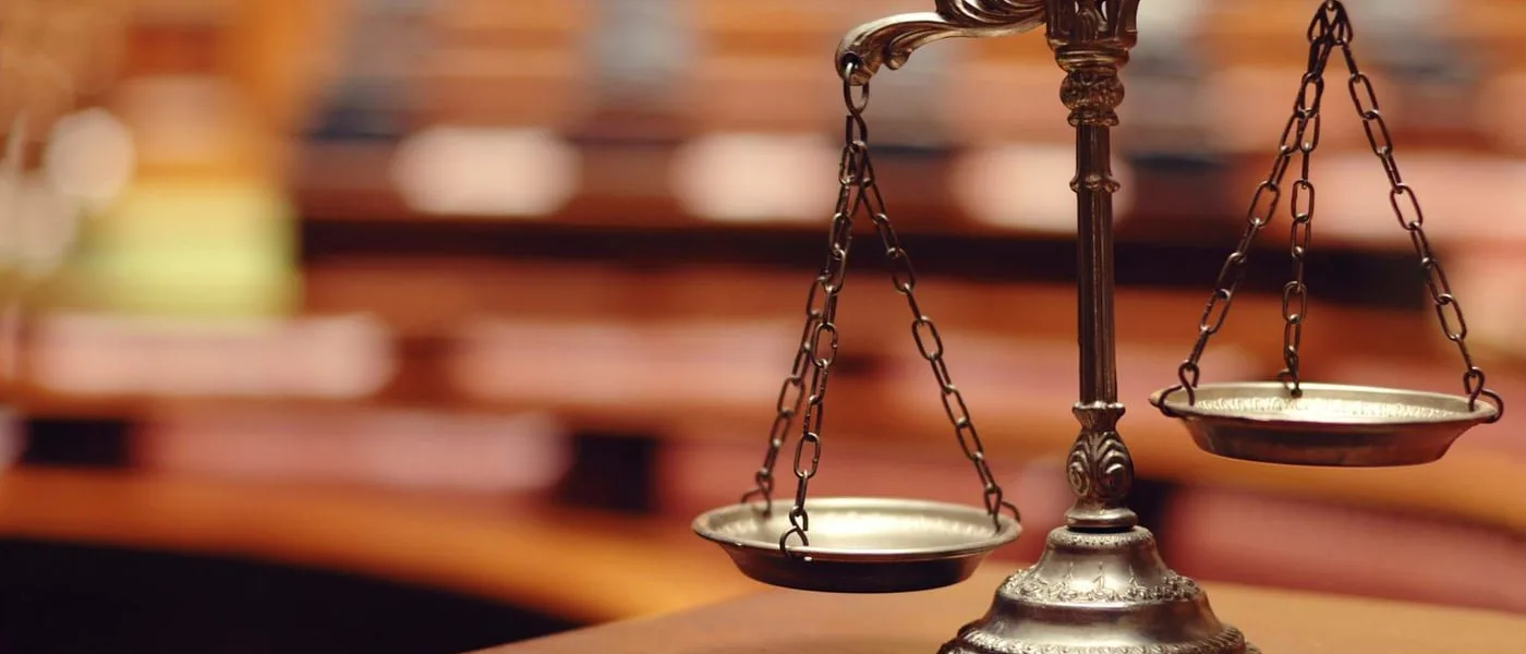 Brass justice scales on a wooden table symbolizing legal battles between billionaire families